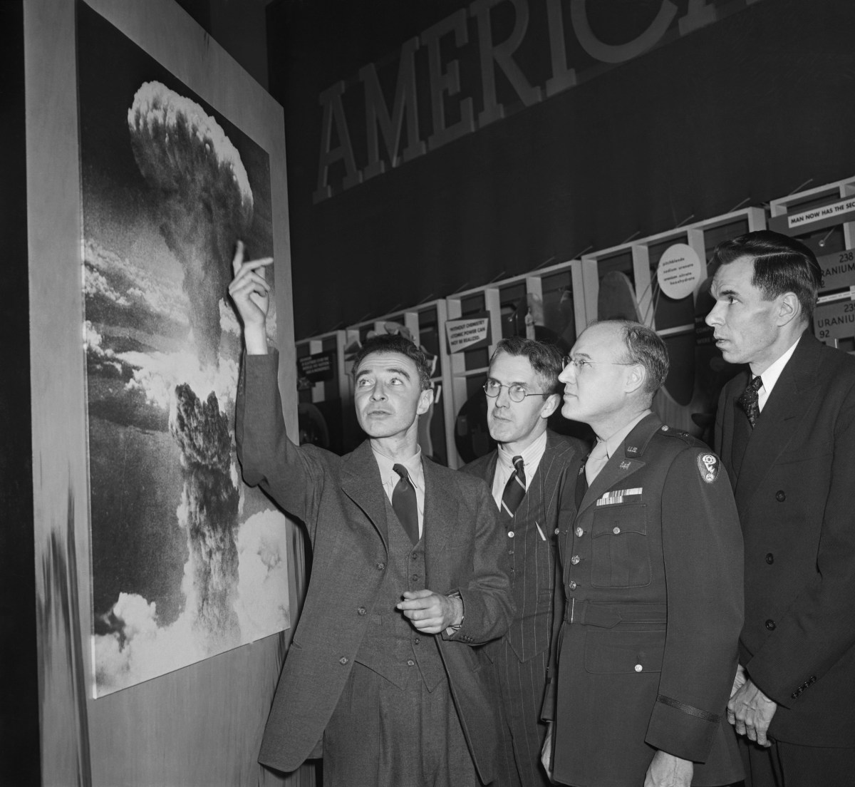 J. Robert Oppenheimer, who was in charge of the Los Alamos, New Mexico, atomic bomb experiment, points to a photograph of the huge column of smoke and flame caused by the actual use of the bomb on Hiroshima, Japan. (Getty Images)