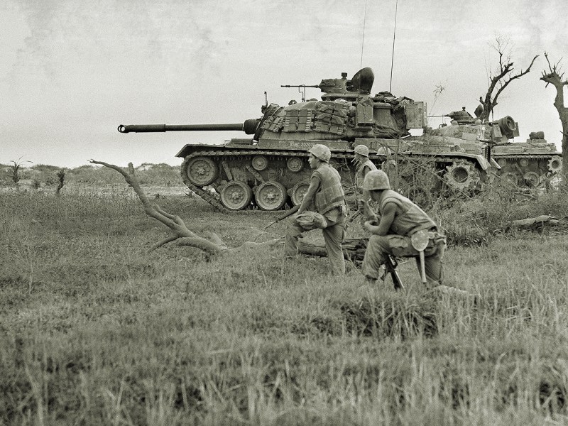 A tank offers support to a group of U.S. Marines awaiting signal to advance on trapped North Vietnamese unit near Da Ha near the DMZ, June 24, 1968. (AP Photo/Dana Stone)