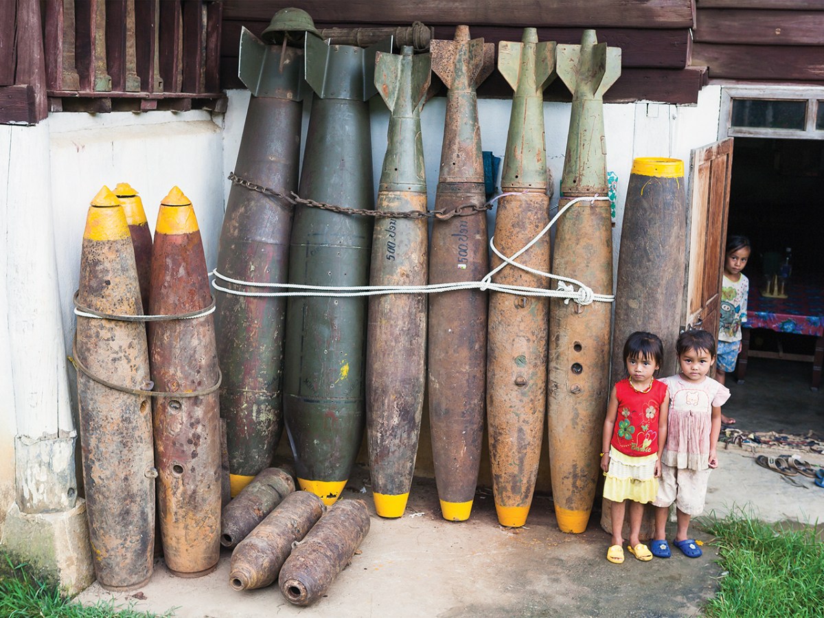 Photo of defused UXO outside a house in Xieng Khouang. Over 30% of the bombs dropped on Laos by the US failed to explode - leaving literally millions of items of ordinance (many of them tiny mine bomblets from cluster bombs) sitting in villages, buried in rice padddies, and scattered over the hillsides. Casualties from UXO are estimated at 12,000 since 1973. A substantial industry in scrap metal has arisen from the abundance of recoverable (but still fused) bombs, both due to its relative lucrativeness (compared with growning rice), and also out of desperation, as thousands of hectares of land has been rendered unfarmable until cleared of UXO. Once defused, much of this war scrap is also put to practical use; cluster bomb casings are used as planters and house stilts, bomb cases for fencing and jettisoned fuel tanks converted into fishing boats.
