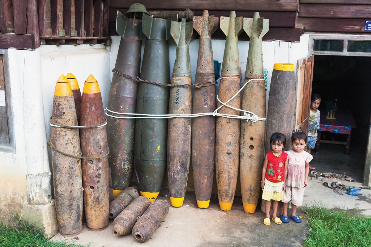 Photo of defused UXO outside a house in Xieng Khouang. Over 30% of the bombs dropped on Laos by the US failed to explode - leaving literally millions of items of ordinance (many of them tiny mine bomblets from cluster bombs) sitting in villages, buried in rice padddies, and scattered over the hillsides. Casualties from UXO are estimated at 12,000 since 1973. A substantial industry in scrap metal has arisen from the abundance of recoverable (but still fused) bombs, both due to its relative lucrativeness (compared with growning rice), and also out of desperation, as thousands of hectares of land has been rendered unfarmable until cleared of UXO. Once defused, much of this war scrap is also put to practical use; cluster bomb casings are used as planters and house stilts, bomb cases for fencing and jettisoned fuel tanks converted into fishing boats.