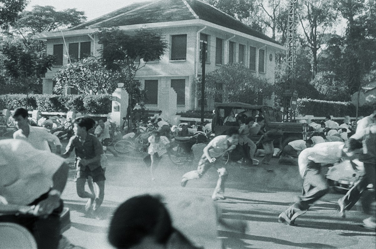 Photo of South Vietnam: Failed Coup In Saigon Against President Ngo Dinh Diem. Saigon- 17 novembre 1960- Lors du coup d'état manqué contre le président NGO DINH DIEM, des jeunes gens (révolutionnaires) accourent dans une rue, lâchant leur bicyclette pour se protéger de coups de feu, un camion militaire derrièer eux dans une rue, une demeure en arrière-plan.