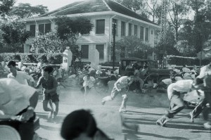 Photo of South Vietnam: Failed Coup In Saigon Against President Ngo Dinh Diem. Saigon- 17 novembre 1960- Lors du coup d'état manqué contre le président NGO DINH DIEM, des jeunes gens (révolutionnaires) accourent dans une rue, lâchant leur bicyclette pour se protéger de coups de feu, un camion militaire derrièer eux dans une rue, une demeure en arrière-plan.