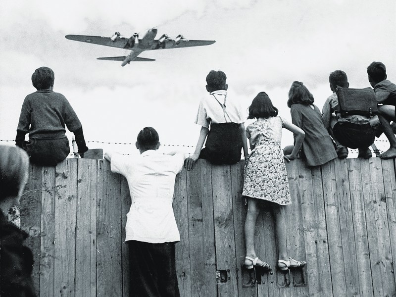 Photo of West Berlin children perched on the fence of Tempelhof airport watch the fleets of U.S. airplanes bringing in supplies in 1948 to circumvent the Russian blockade of land and waterways. The airlift began June 25, 1948 and continued for 11 months.