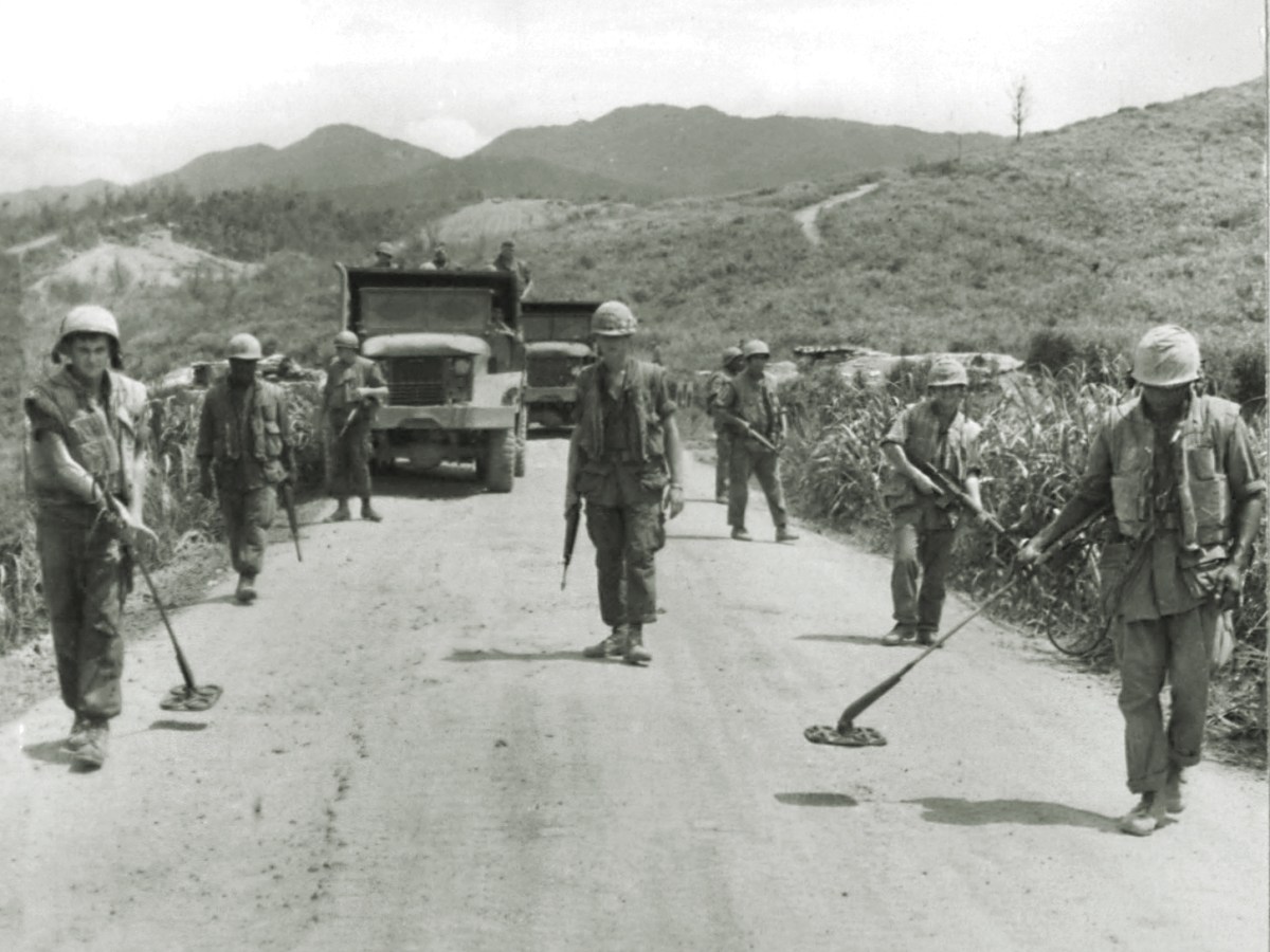 Photo of a Marine mine sweep team checks a road west of Ca Lu for enemy mines in 1968, a duty performed every morning.