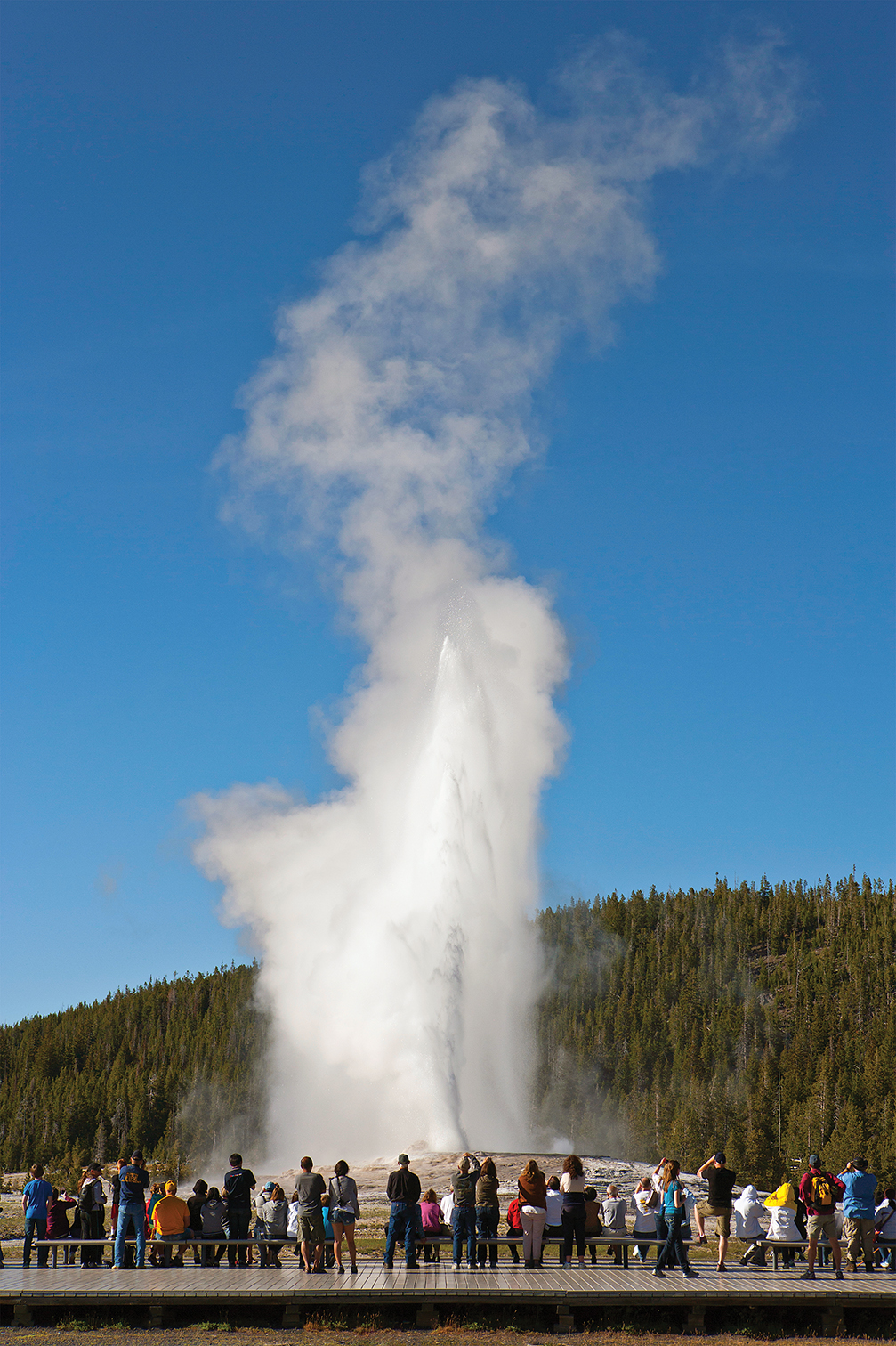 Photo of tourists watching Old Faithful, Yellowstone National Park.