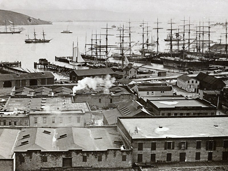 Photo of a crowded harbor scene with buildings and ships docked in slips or sailing around the harbor. San Francisco harbor from Telegraph Hill, Calif.